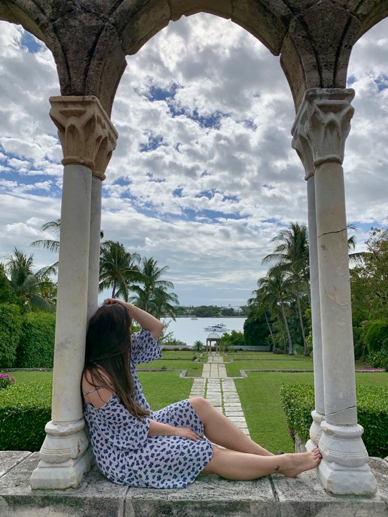 Looking out through a stone arch toward a yacht and gardens
