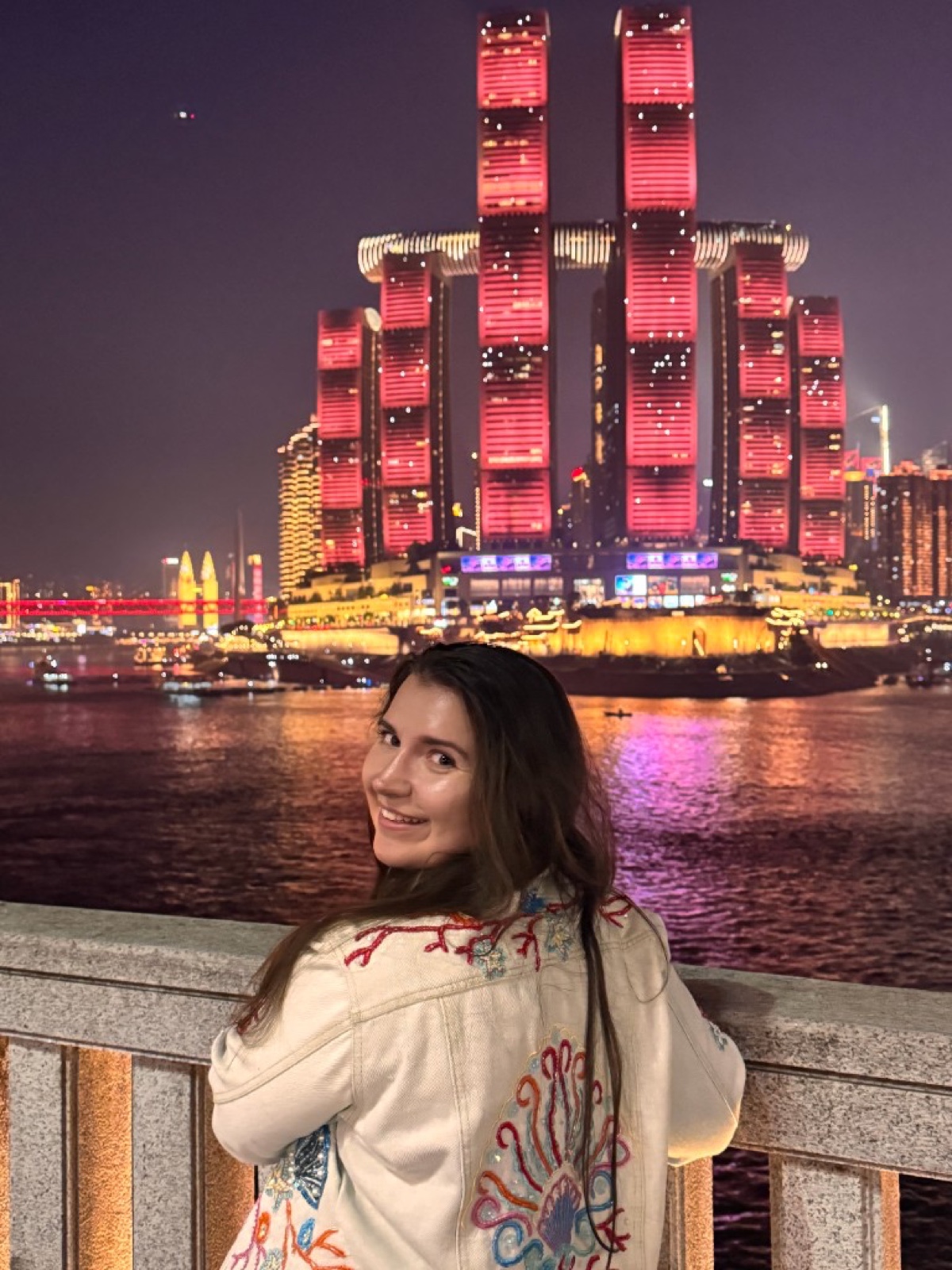 Anna in Chongqing at night, with the city lights behind