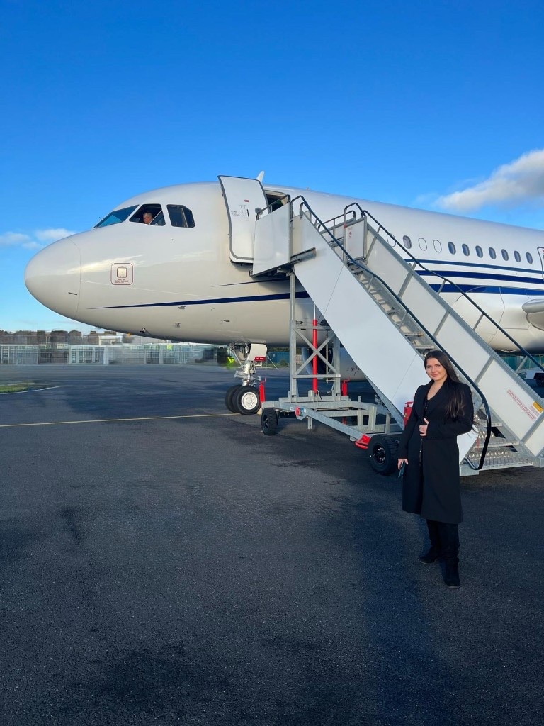 Anna beside a private jet on the tarmac